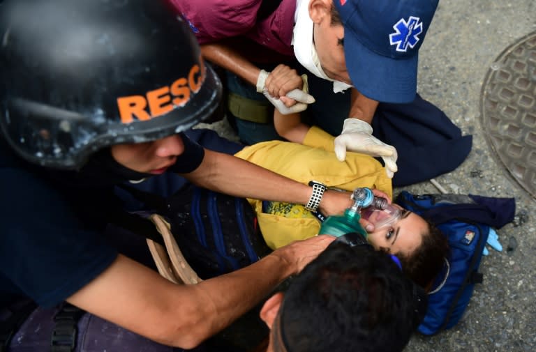 Rescue workers assist a woman after clashes with the riot police during a protest against Venezuelan President Nicolas Maduro, in Caracas on April 20, 2017