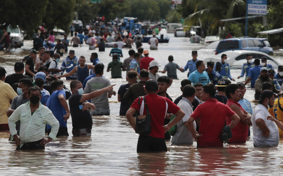 Residents wade through a flooded road in the aftermath of Hurricane Eta in Planeta, Honduras, Thursday, Nov. 5, 2020. The storm that hit Nicaragua as a Category 4 hurricane on Tuesday had become more of a vast tropical rainstorm, but it was advancing so slowly and dumping so much rain that much of Central America remained on high alert. (AP Photo/Delmer Martinez)