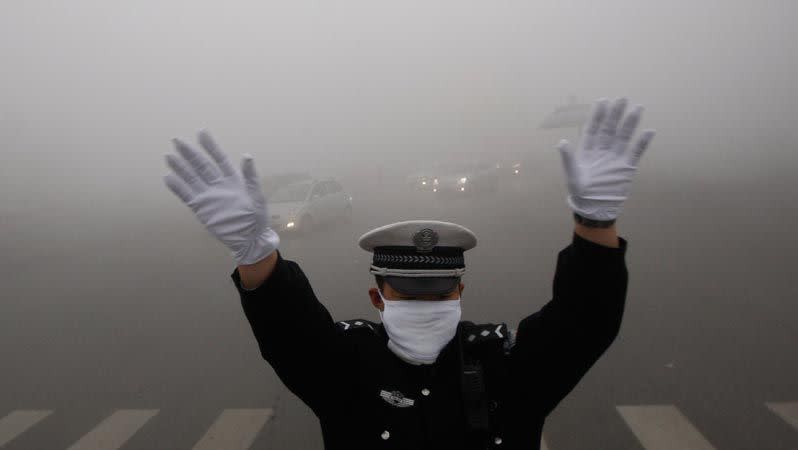 A traffic policeman signals to drivers during a smoggy day in Harbin, Heilongjiang province. Photo: Reuters