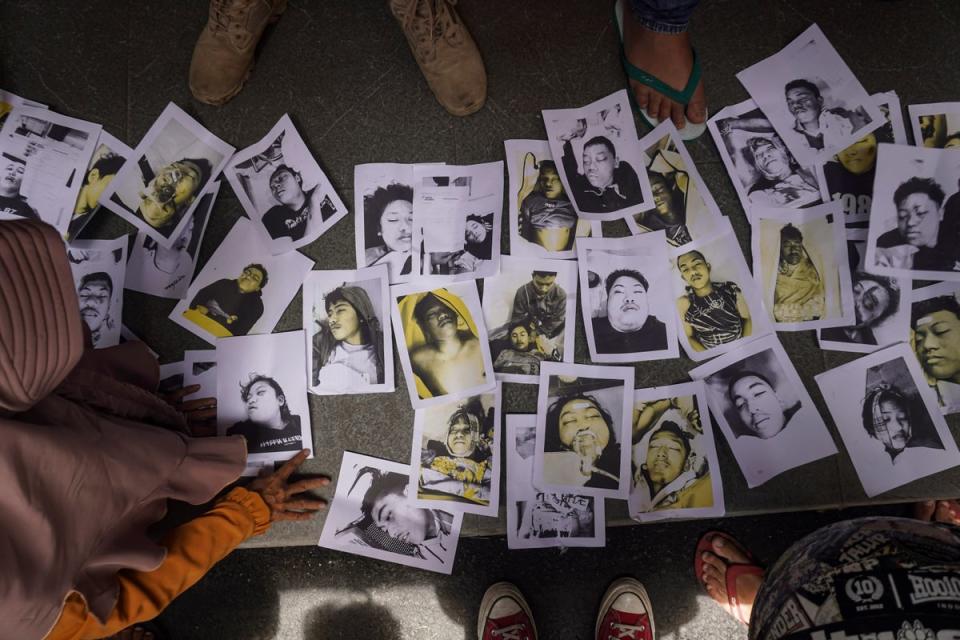 People looking for their relatives inspect photographs of football riot victims provided by volunteers to help them identify their family members in Malang (AP)