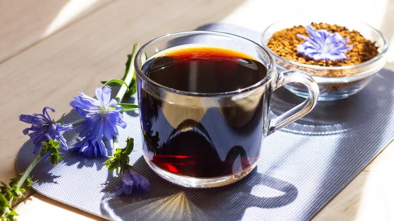 A  brewed mug of chicory coffee next to chicory flowers