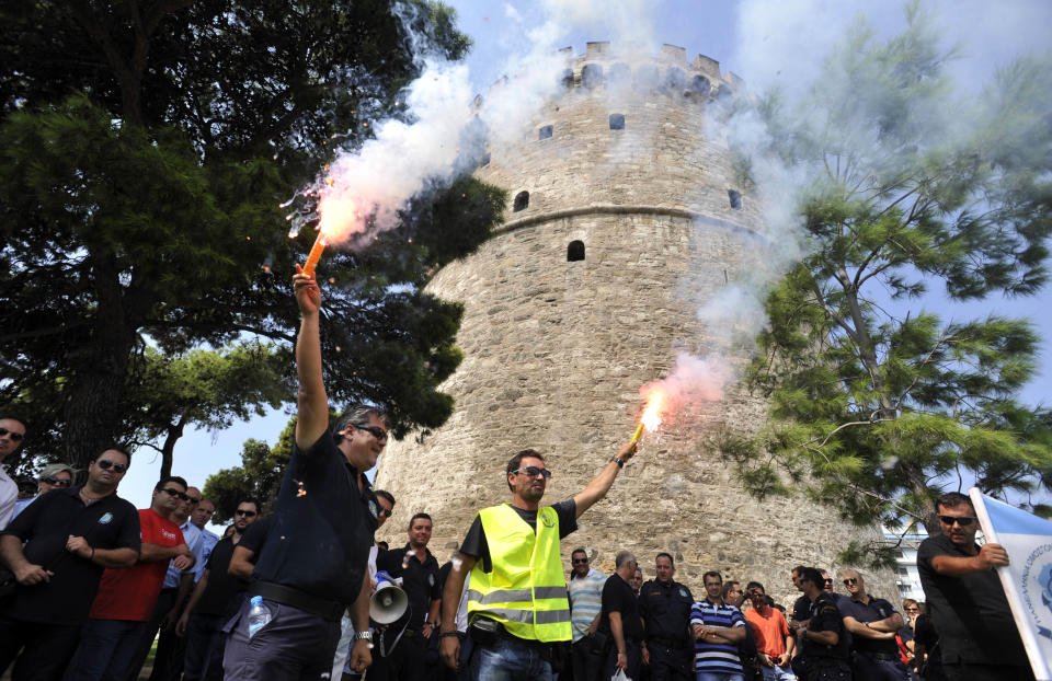 Coast guards hold flares and shout slogans in front of White Tower, city's landmark, during a protest in the northern Greek port city of Thessaloniki, Saturday, Sept. 8, 2012. Greece, in the grip of a severe recession for the fifth straight year, is still struggling to avoid bankruptcy by imposing harsh austerity measures, including wage and pension cuts. Unemployment has soared to nearly a quarter of the workforce. (AP Photo/Giorgos Nissiotis)