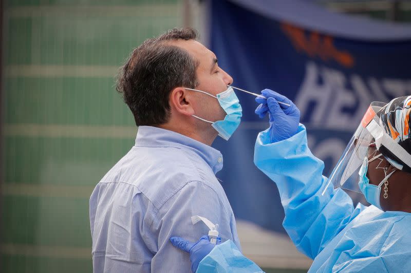 FILE PHOTO: A health worker takes a swab sample from a man to test for the coronavirus disease (COVID-19) in the Borough Park in Brooklyn, New York