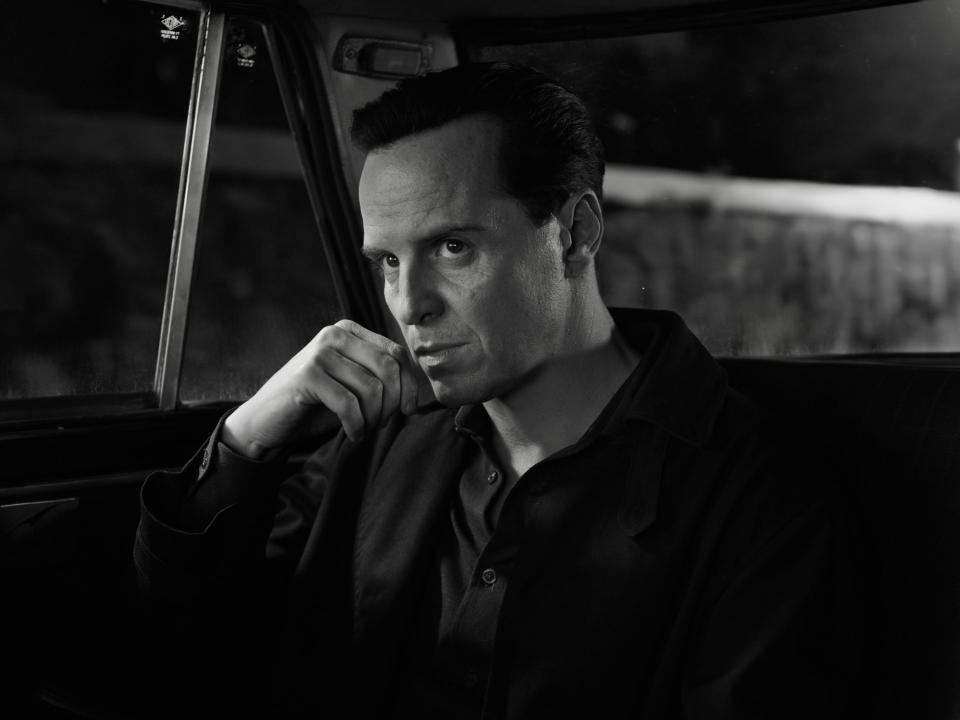 andrew scott, seen in black and white, sitting in the back of a car looking intent