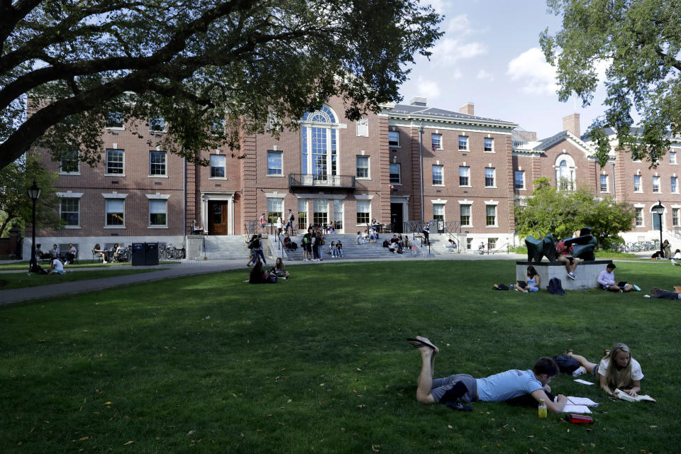 In this Sept. 25, 2019, photo, people rest on grass while reading at Brown University in Providence, R.I. Tax and charity records show that prestigious universities around the world, including Brown, have accepted at least $60 million from the family that owns OxyContin maker Purdue Pharma over the past five years, even as the company has been embroiled in lawsuits over its role in the opioid epidemic. (AP Photo/Steven Senne)