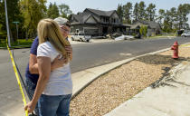 Joslyn Youd, 21, gets a hug from her aunt Nikki Ewell outside a damaged house, background, after a plane operated by Youd's father crashed in Payson, Utah, Monday, Aug. 13, 2018. A Utah man flew the small plane into his own house early Monday just hours after he had been arrested for assaulting his wife in a nearby canyon where the couple went to talk over their problems, authorities said. (Leah Hogsten/The Salt Lake Tribune via AP)