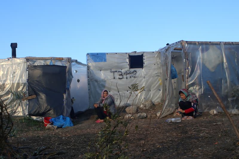 FILE PHOTO: Women sit next to tents, at a makeshift camp for refugees and migrants next to the Moria camp, on the island of Lesbos