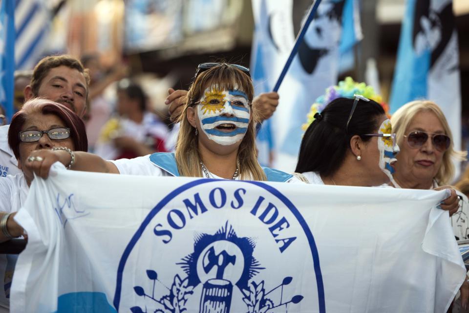 Simpatizantes del candidato presidencial del Partido Nacional, Luis Lacalle Pou, sostiene una bandera del partido durante su cierre de campaña en Las Piedras, Uruguay, el miércoles 20 de noviembre de 2019. (AP Foto/Matilde Campodonico)