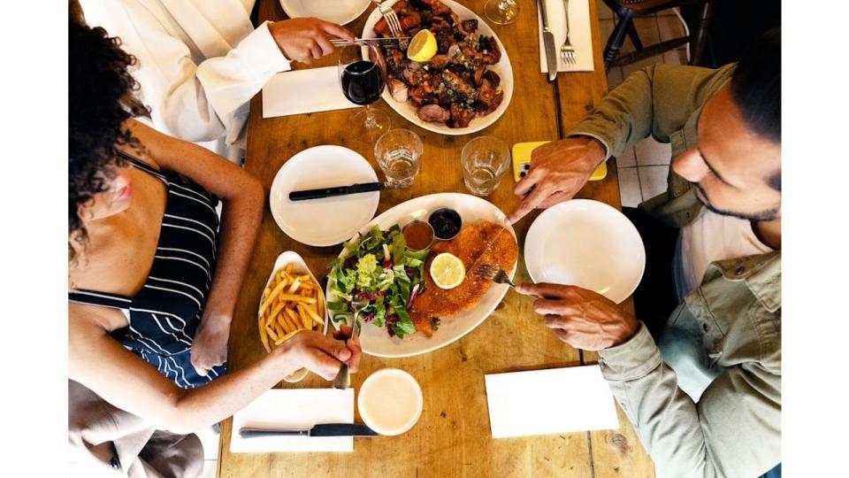 overhead close  up shot group of friends eating in restaurant and sharing dishes