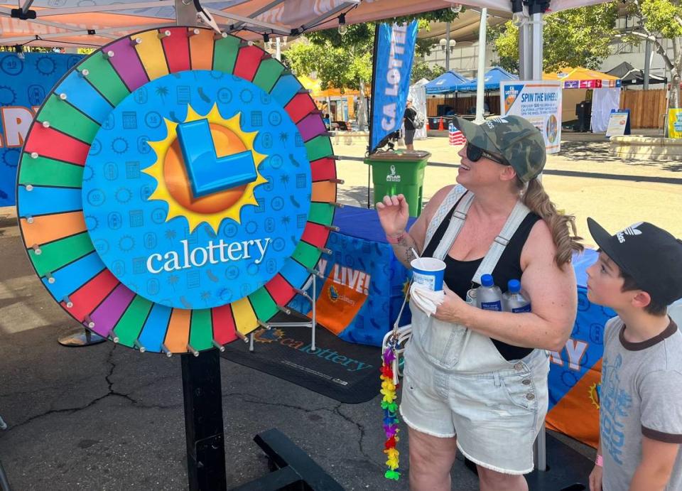 Kirstin Mace, left, and Jaxon Mace, 8, wait for the wheel to stop spinning at the CA Lottery Live! booth at the California State Fair on Friday, July 26, 2024.