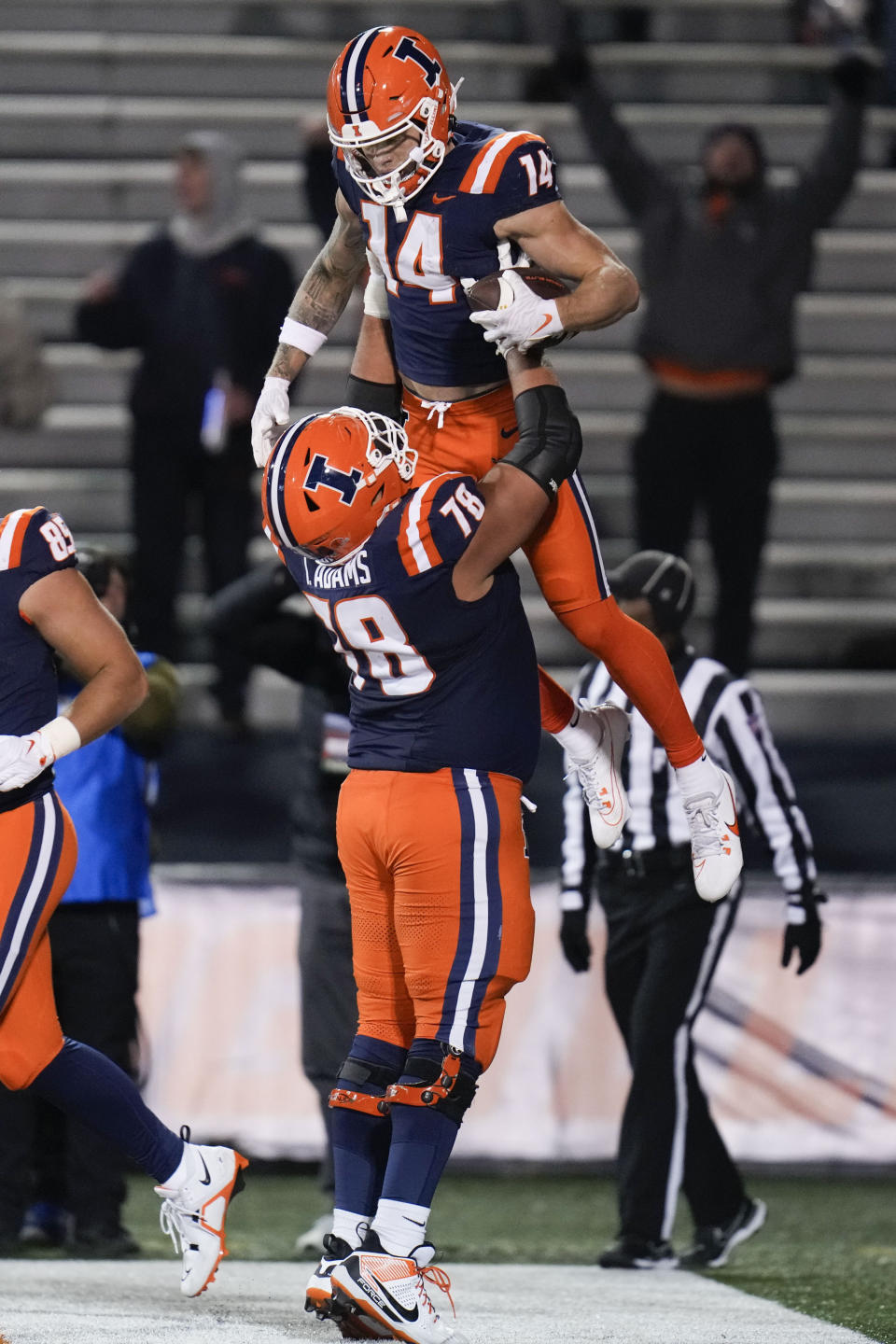 Illinois offensive lineman Isaiah Adams (78) hoists wide receiver Casey Washington (14) after Washington scored a touchdown during the second half of an NCAA college football game against Northwestern, Saturday, Nov. 25, 2023, in Champaign, Ill. (AP Photo/Erin Hooley)