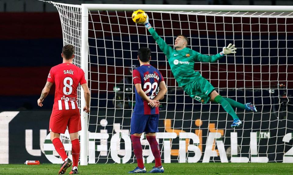 Barcelona's Iñaki Peña saves a free kick from Atletico's Memphis Depay by leaping to the right and extending his right arm.