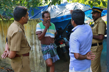 K M Ashokan (2-L), father of 24-year-old Akhila, who converted to Islam in 2016 and took a new name, Hadiya, smokes while speaking with a friend, as police officers stand guard outside his house at Vaikom in the Kottayam district of the southern state of Kerala, November 23, 2017. REUTERS/Sivaram V