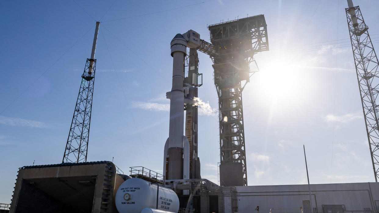  A white rocket stands on its launch pad on a sunny, clear morning. 