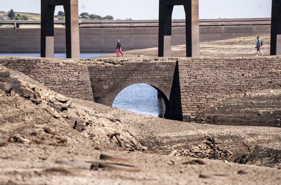 People walk on the dry cracked earth at Baitings Reservoir in Ripponden, West Yorkshire, where water levels are significantly low. The total stock of water in England's reservoirs at the end of July was 65 percent of its normal capacity - the lowest level for that point in the calendar year since 1995, the Environment Agency has said. Picture date: Friday August 12, 2022. (Photo by Danny Lawson/PA Images via Getty Images)