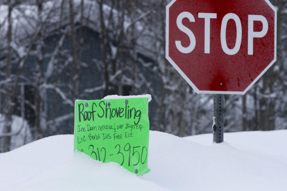 A sign advertising roof shoveling is shown Monday, Jan. 29, 2024, in Anchorage, Alaska. A recent storm dropped over 14 inches of snow on Anchorage, bringing the seasonal total to over 101 inches. It's the earliest Alaska's largest city has reached the 100-inch mark. (AP Photo/Mark Thiessen)