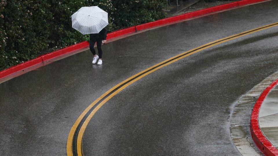 A Cal Poly student turns her umbrella into the wind-driven rain on the road between the parking structure and Davidson Music Building as another atmospheric river storm hits the Central Coast on March 14, 2023. David Middlecamp/dmiddlecamp@thetribunenews.com