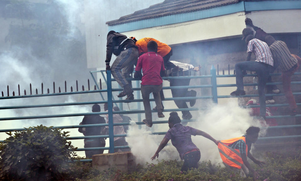 Opposition supporters climb over a fence and into the University of Nairobi campus as they flee from clouds of tear gas fired by riot police during a protest in downtown Nairobi, May 16, 2016. Kenyan police have tear-gassed and beaten opposition supporters during a protest demanding the disbandment of the electoral authority over alleged bias and corruption. (AP Photo/Ben Curtis)