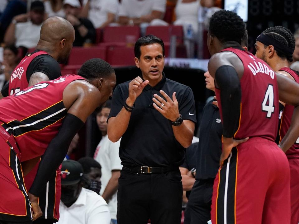 Erik Spoelstra speaks while surrounded by Heat players during a game.