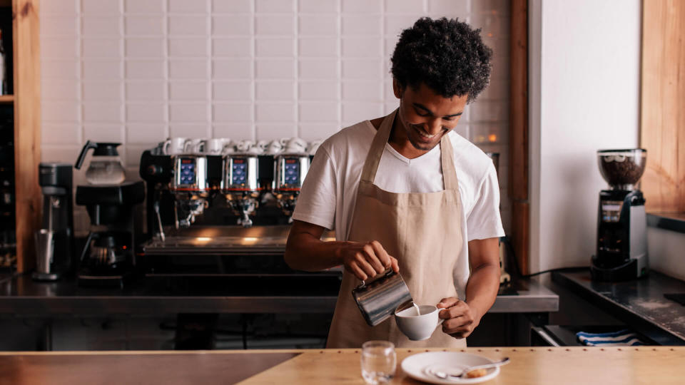 young-african-man-pouring-milk-into-coffee