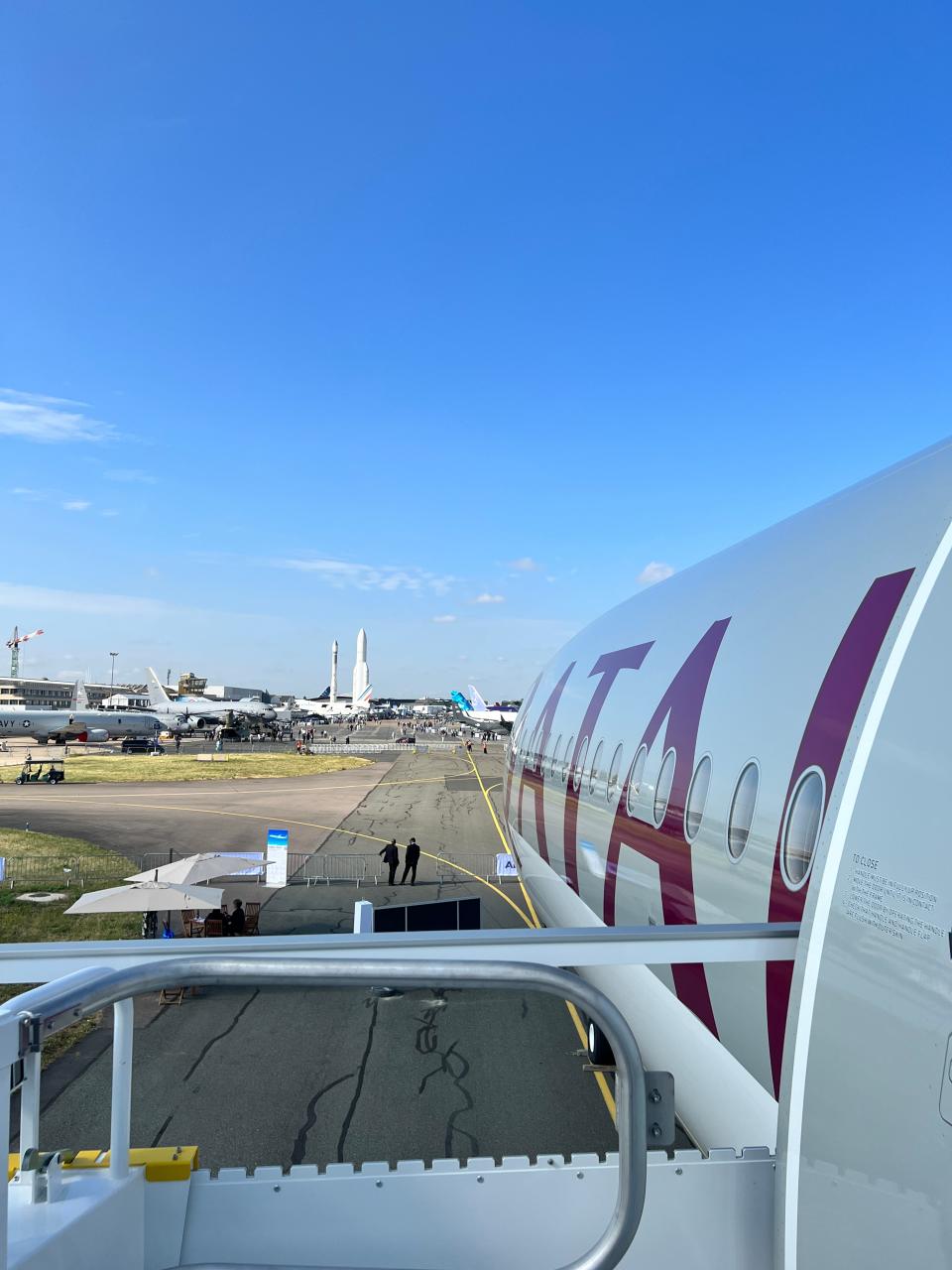 The Qatar Airways logo on the side of an A350, and the Paris Air Show visible in the background — including military planes, and two rockets