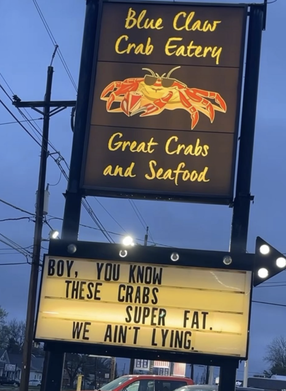 Signboard for Blue Claws Crab Eatery advertising "Great Crabs and Seafood" with a humorous message that says, "Boy, you know these crabs super fat. We ain't lying"