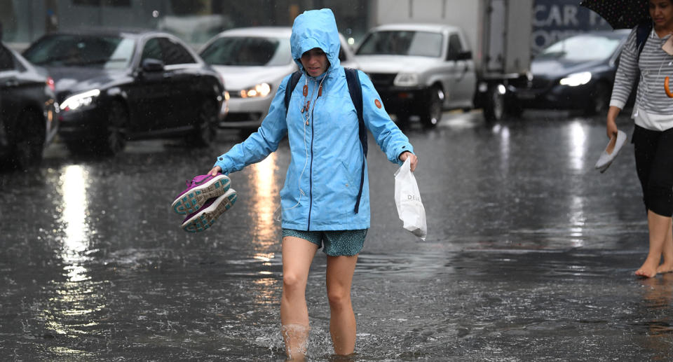 Redestrians walk through flood waters at the corner of Clarendon and Cecil Street in South Melbourne, December 13, 2018