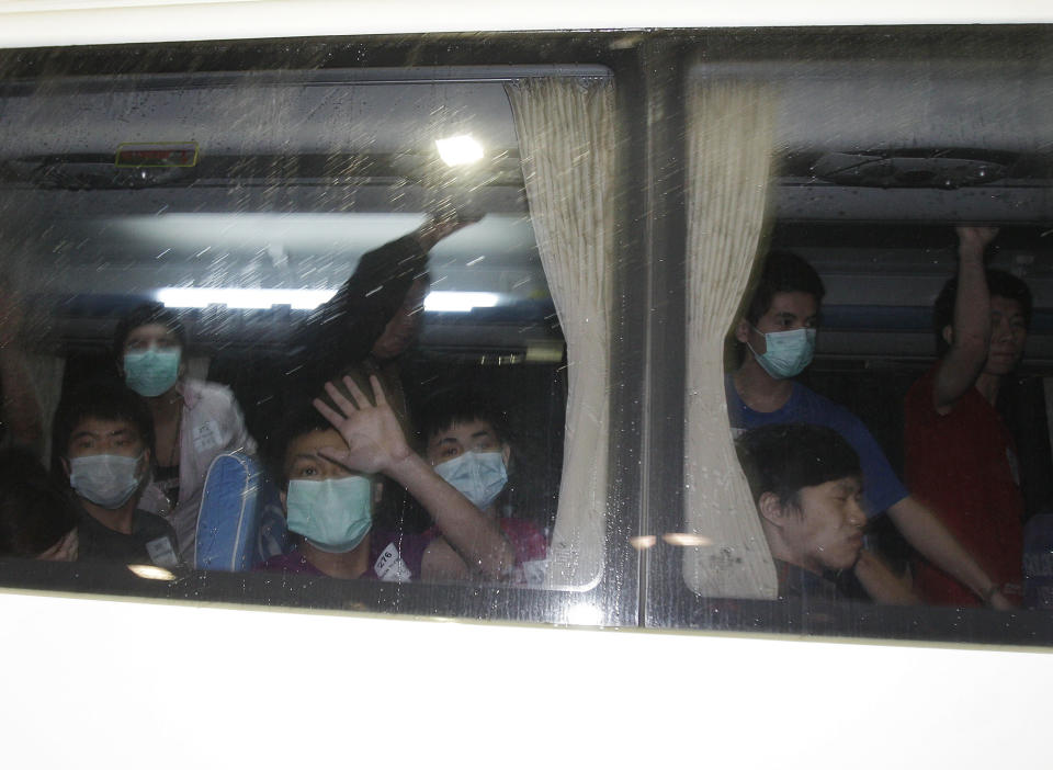 Taiwanese, suspected of being members of a fraud syndicate, wave from the window of their bus as they arrive at Manila's International Airport, Philippines early Wednesday Sept. 19, 2012. About 279 Taiwanese were deported following their arrest for alleged online fraud. One died while others began falling ill in crowded makeshift detention facilities, officials said. (AP Photo/Aaron Favila)