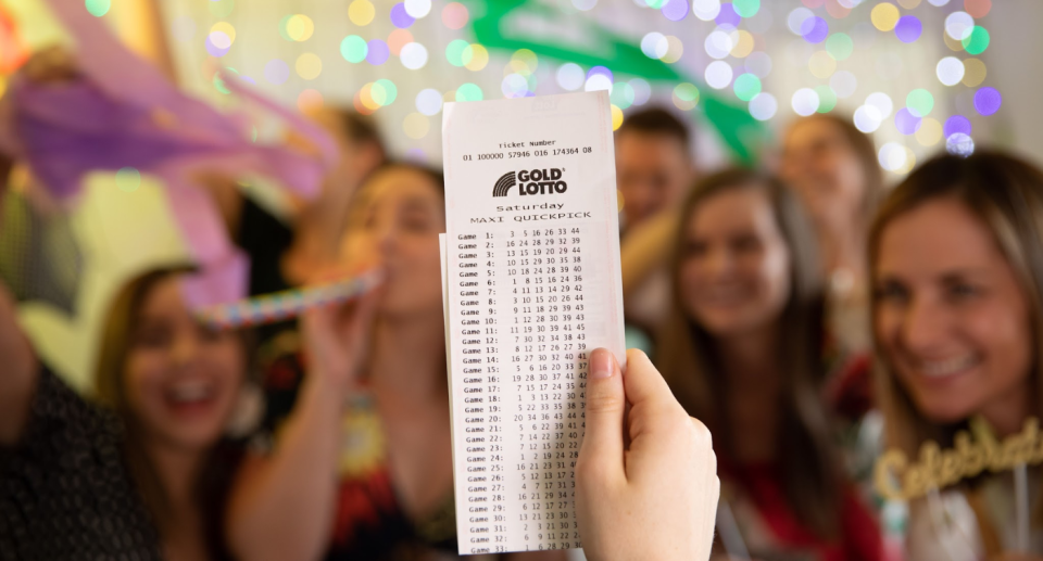 Image of Saturday Gold Lotto ticket with group celebrating in the background.