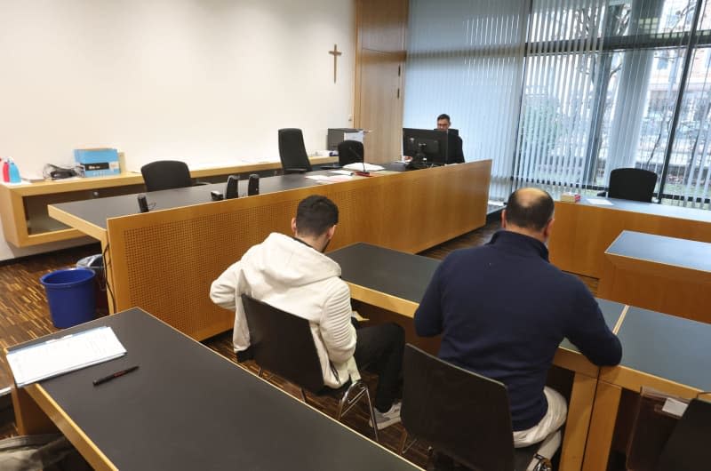 The 19-year-old defendant (L) sits next to his interpreter in a courtroom in the criminal justice center. A German court sentenced a man to a juvenile prison term on Wednesday in connection with the tearing down of an Israel flag hung in front of Augsburg City Hall in Bavaria. Karl-Josef Hildenbrand/dpa