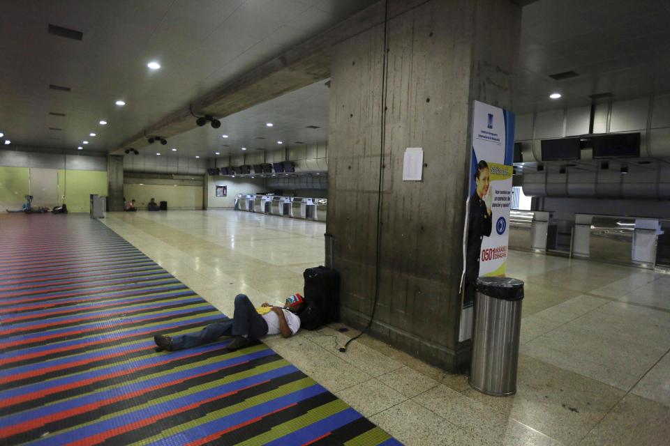 A man sleeps near to Air France desk at Simon Bolivar International Airport in Maiquetia near Caracas, Venezuela, Saturday, Dec. 14, 2013. Venezuelan bomb experts are inspecting a grounded Air France flight after being tipped off by French authorities that a terrorist group may be planning to detonate an explosive device in midair. Venezuelan Interior Minister Miguel Rodriguez Torres told state TV that a team of more than 60 technicians are performing an exhaustive search of the aircraft that will take several hours before the flight can be reprogrammed.(AP Photo/Fernando Llano)