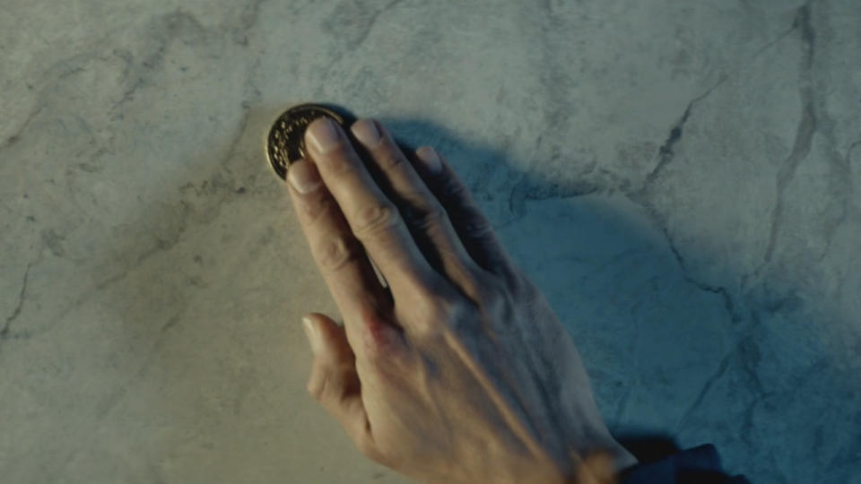 A gold coin being placed on a counter at The Continental in John Wick.