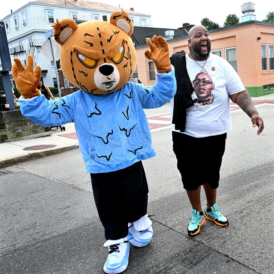 Cheniel Garcia, right, arrives at the Framingham Downtown Common with "Drippy the Bear," the mascot for his L's Up Entertainment venture as the hip-hop artist Young Biggs, Sept. 3, 2022. Garcia was holding a "Neighborhood Give Back" event, offering free pizza and care packages to the city's homeless.