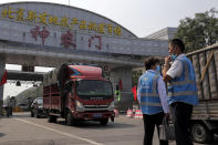 Officers with vests wearing face masks to help curb the spread of the coronavirus watch trucks exit the checkpoint outside the Xinfadi wholesale food market district in Beijing, Sunday, Sept. 6, 2020. According to local news report, Xinfadi market, the capital's biggest wholesale food market have reopen for wholesale operation after it was shutdown following the coronavirus outbreak. China's government on Sunday reported several new coronavirus infections, all believed to have been acquired abroad, and no deaths. (AP Photo/Andy Wong)