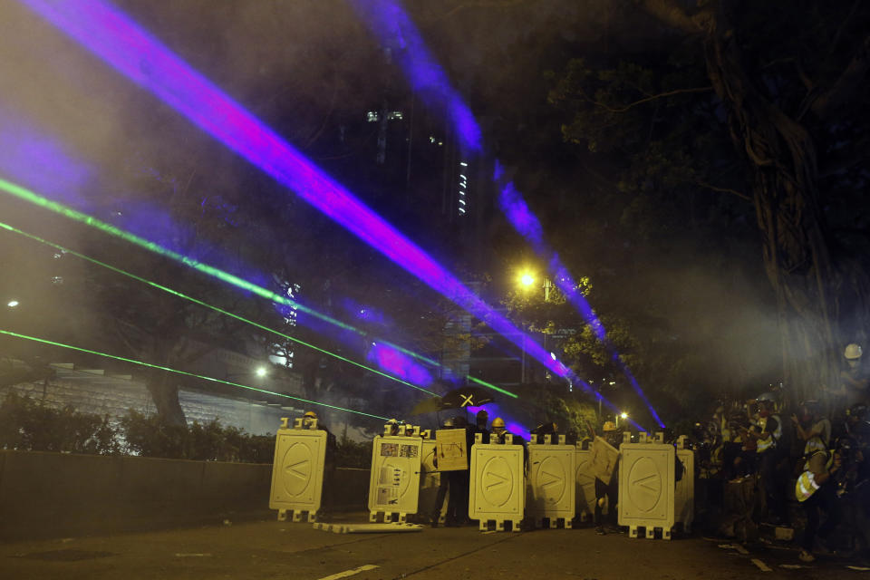 Protesters huddle behind barriers and use laser beams to shine at riot police during confrontation in Tsim Sha Tsui in Hong Kong on Saturday, Aug. 3, 2019. Hong Kong protesters ignored police warnings and streamed past the designated endpoint for a rally Saturday in the latest of a series of demonstrations targeting the government of the semi-autonomous Chinese territory. (Steve Leung/HK01 via AP)