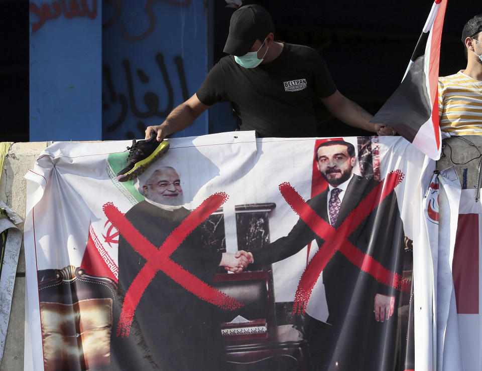 A poster of Iraq Parliament Speaker Mohammed al-Halbousi, right, and Iran President Hassan Rouhani, left, hang on a building near Tahrir Square, during ongoing protests in Baghdad, Iraq, Wednesday, Nov. 6, 2019. (AP Photo/Hadi Mizban)