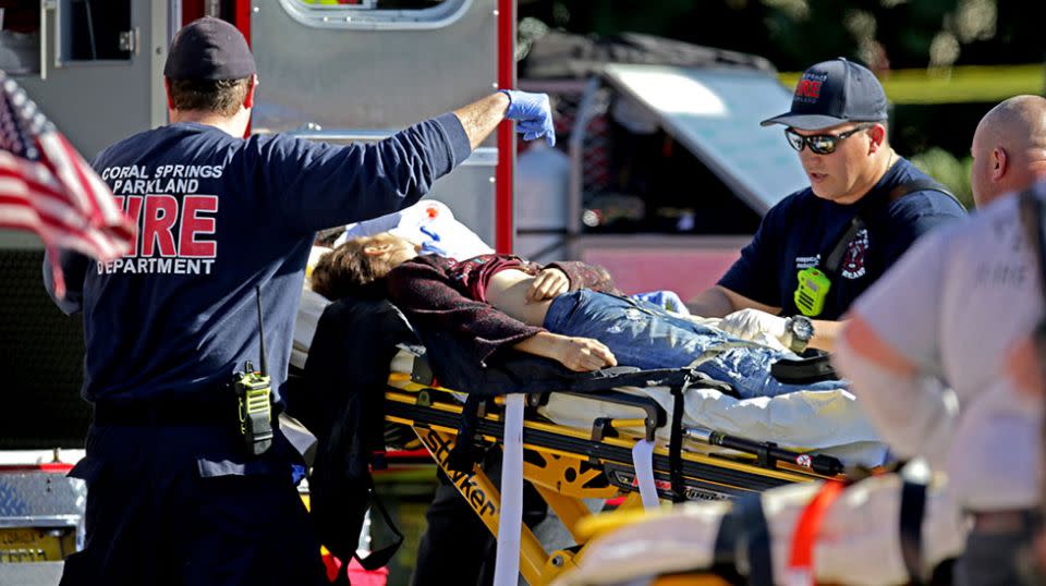 A woman is rushed from the school by paramedics after the shooting. 17 people died after being shot. Source: Getty