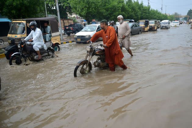 Commuters make their way through a flooded street after heavy rains in Karachi on September 13, 2022. (Photo: RIZWAN TABASSUM via Getty Images)