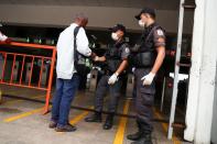 Police officers wearing protective face masks check a passenger's documents before entering the ferry station to go to Niteroi, amid the coronavirus disease (COVID-19) outbreak, in Rio de Janeiro