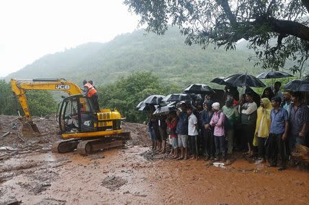 National Disaster Response Force (NDRF) personnel clear the debris as onlookers watch at the site of a landslide at Malin village in the western Indian state of Maharashtra July 31, 2014. REUTERS/Shailesh Andrade