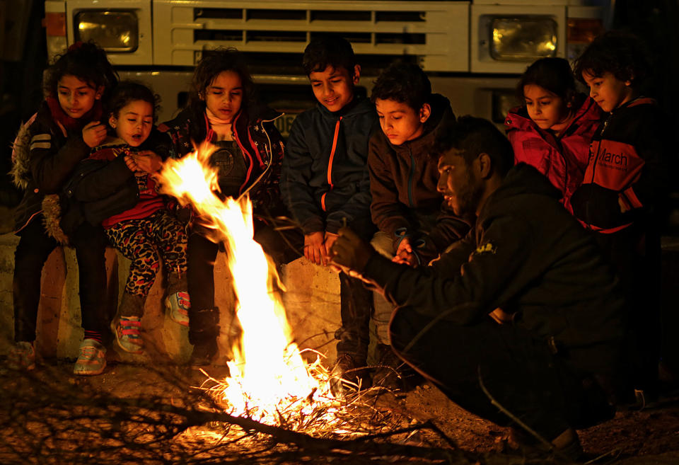 <p>Palestinians travellers’ children warm themselves by a fire while they wait with their families to cross into Egypt through Rafah border crossing between Gaza Strip and Egypt in the southern Gaza Strip, Feb. 7, 2018. (Photo: Mohammed Saber/EPA-EFE/REX/Shutterstock) </p>