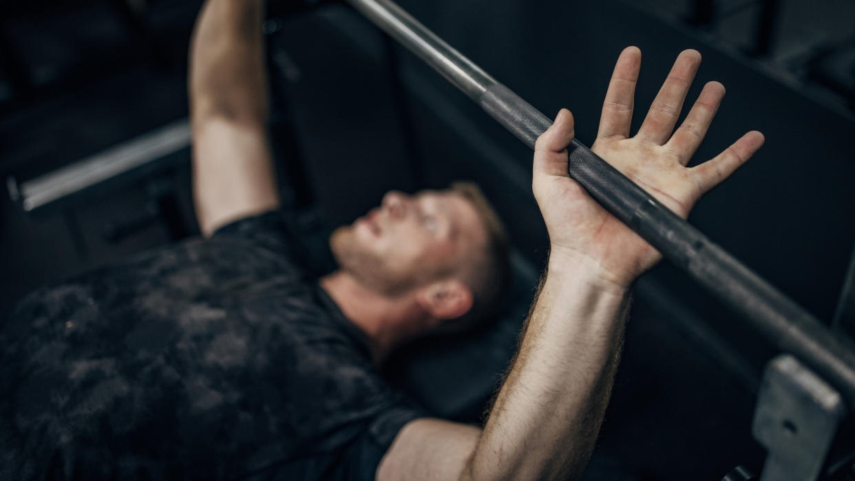  Man on a weight bench  lying under a barbell in a gym. 