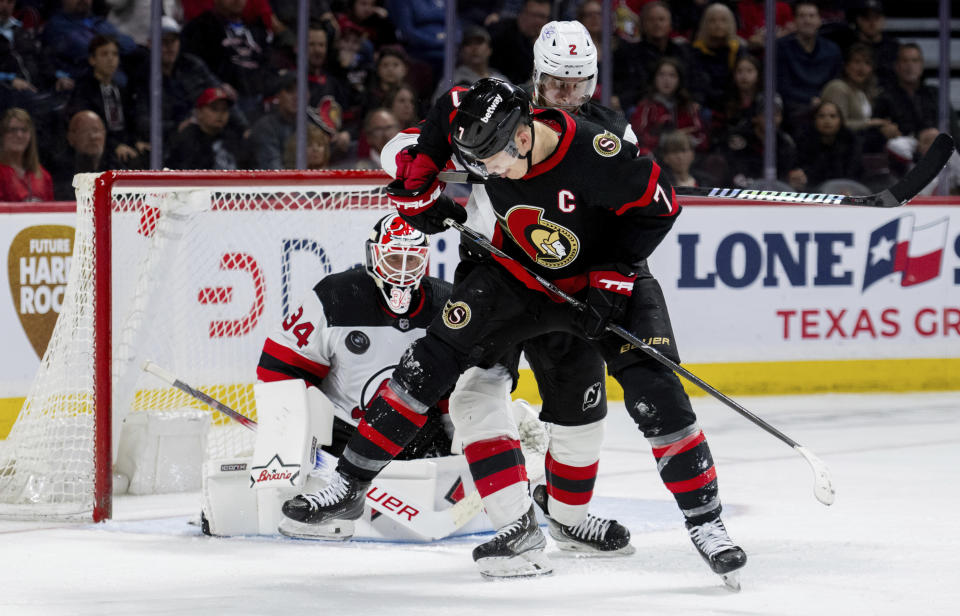 Ottawa Senators left wing Brady Tkachuk (7) attempts to deflect a shot as New Jersey Devils goaltender Jake Allen (34) watches the puck during the third-period NHL hockey game action in Ottawa, Ontario, Saturday, April 6, 2024. (Spencer Colby/The Canadian Press via AP)