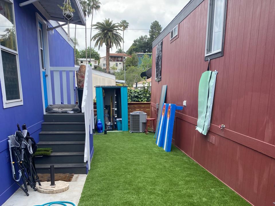 A green area of Astroturf between a blue and a red mobile home