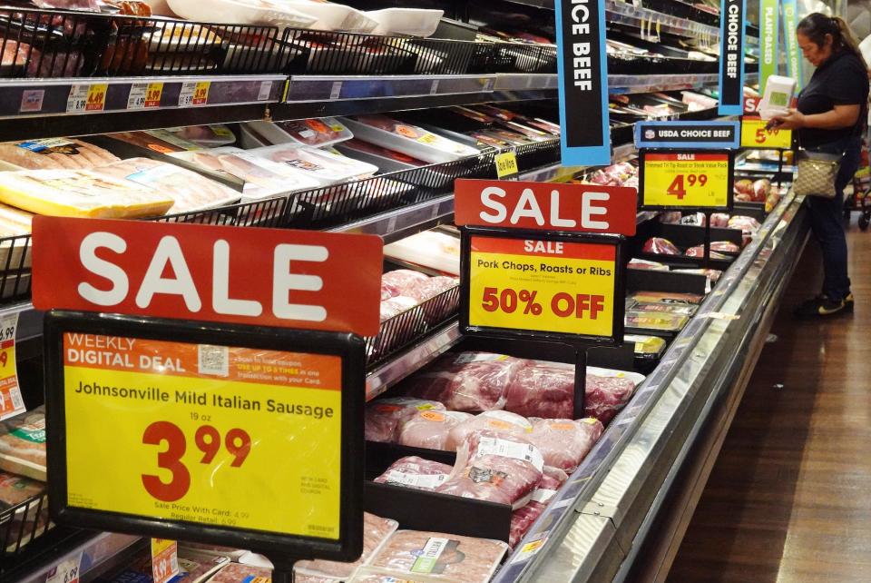 Sale signs at a grocery store and a person shopping at the store