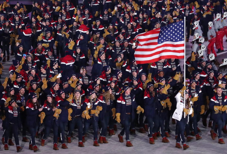 <p>Luger Erin Hamlin of the United States carries the U.S. flag during the Parade of Nations at the opening ceremony, where the team wears uniforms designed by Ralph Lauren. Key items include the fringe suede gloves and intarsia wool sweaters. (Photo: Valery Sharifulin\TASS via Getty Images) </p>