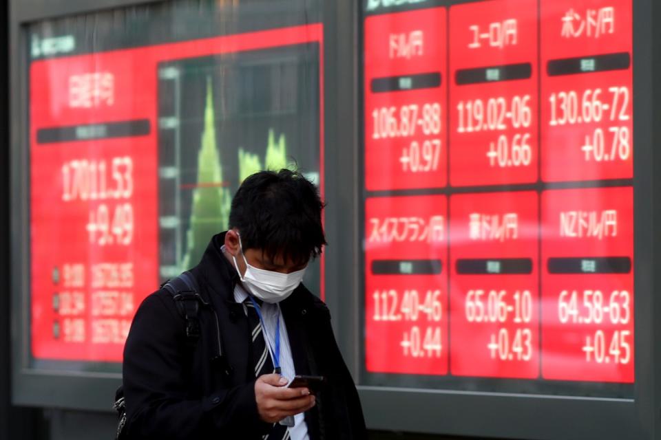 A man walks in front of a stock ticker in Japan