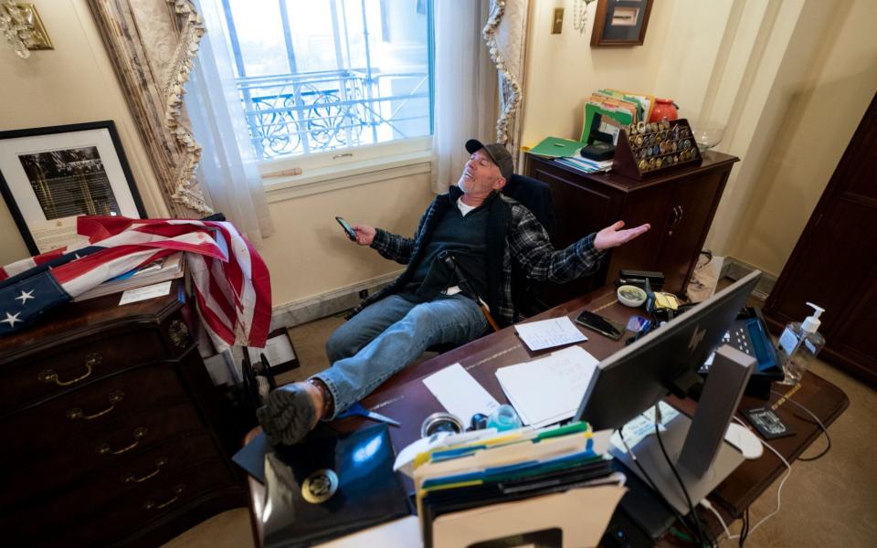 A supporter of US President Donald Trump, Richard Bino Barnett, sits on the desk of US House Speaker Nancy Pelosi - Shutterstock