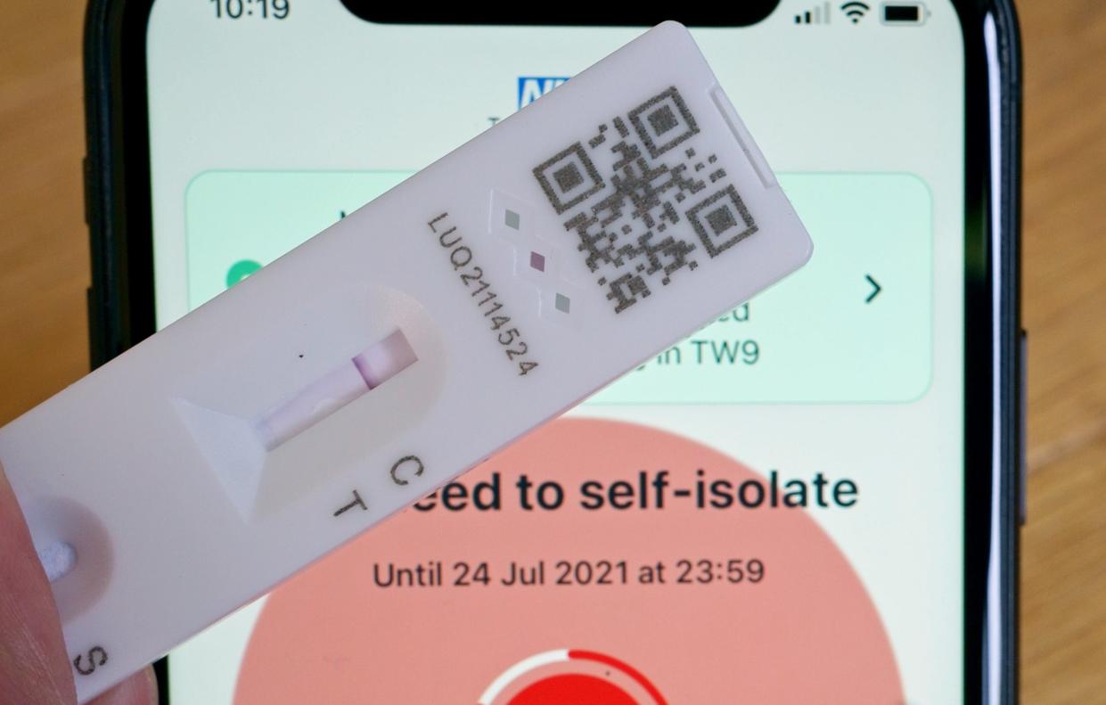 A negative lateral flow test next to advice from the NHS Covid app to self-isolate (PA)