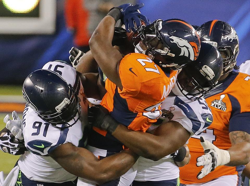 Denver Broncos running back Knowshon Moreno (27) is tackled by Seattle Seahawks defensive end Chris Clemons (91) and defensive end Cliff Avril (56) during the first half of the NFL Super Bowl XLVIII football game Sunday, Feb. 2, 2014, in East Rutherford, N.J. (AP Photo/Matt York)